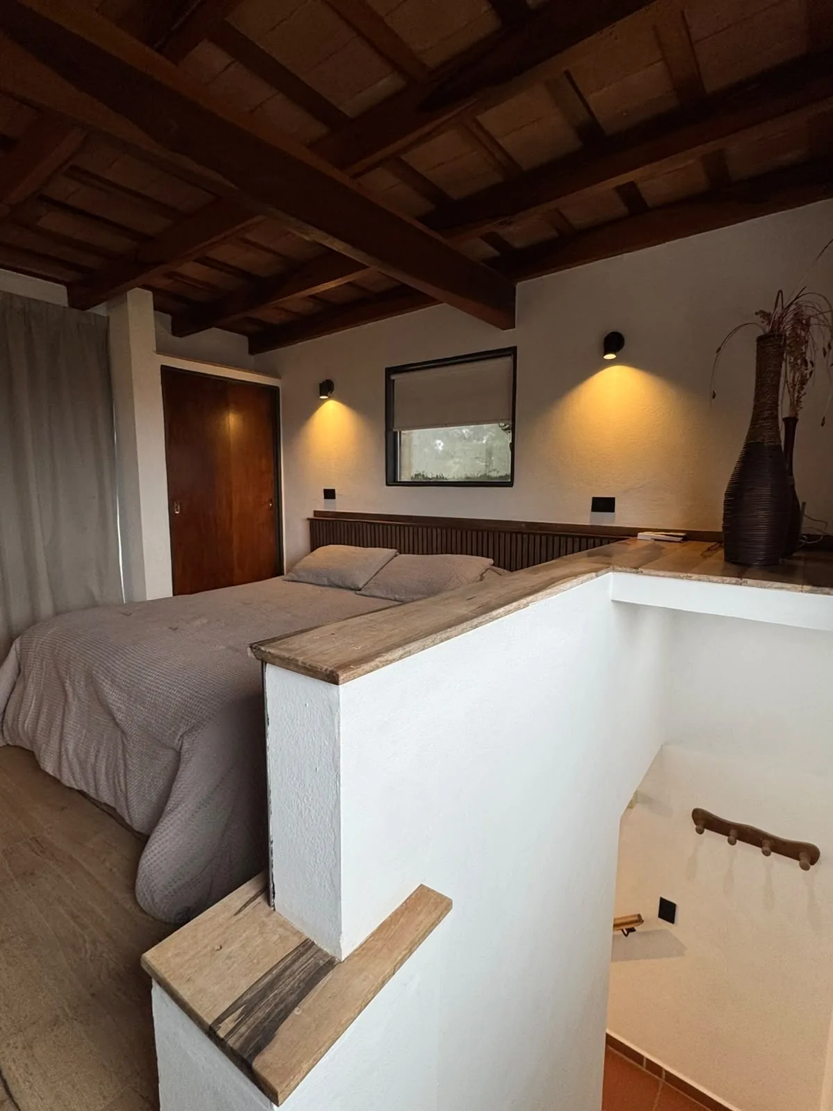 Cama queen de la Casa Amarilla bajo el techo de madera
