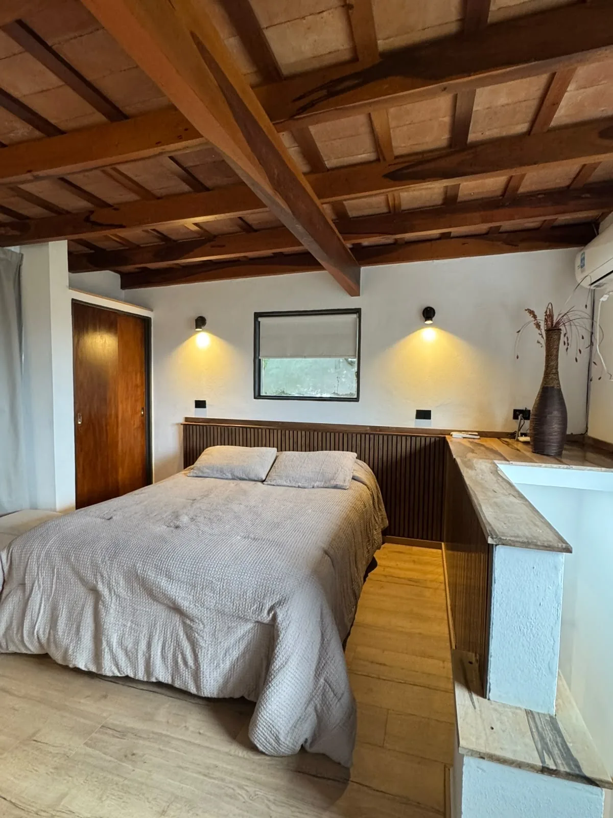 Dormitorio de la Casa Amarilla con cabecera de madera y luz cálida