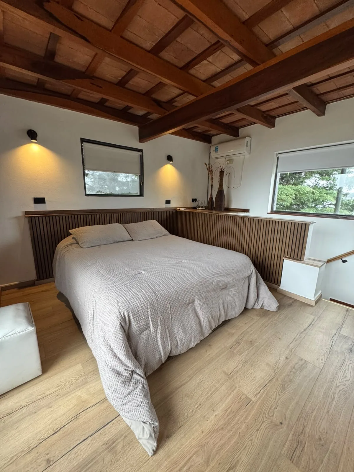 Dormitorio renovado de la Casa Amarilla: cama queen, techo de madera a la vista y piso de madera